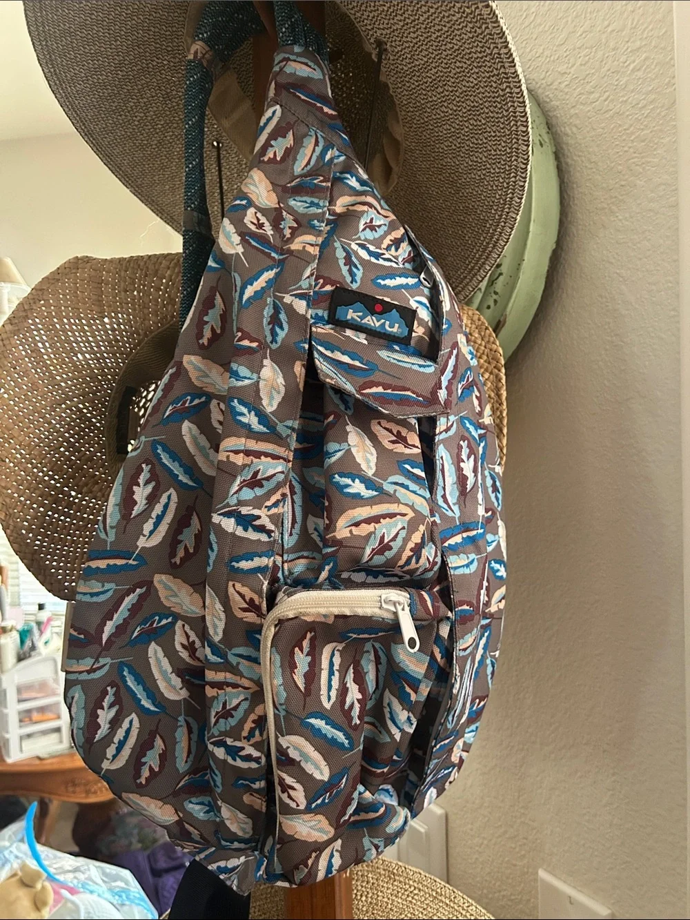 Kavu Brown Sling Backpack with Blue, Cream and Tan Feather Print